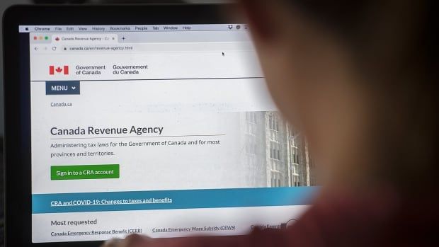 A person looks at a Canada Revenue Agency internet homepage on a computer. The person's face is not visible.