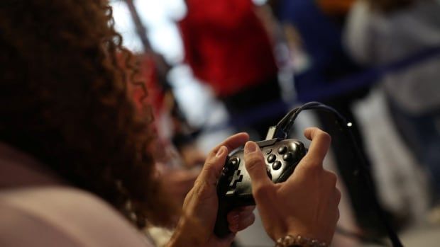 Image of a woman holding a video game controller with two hands.