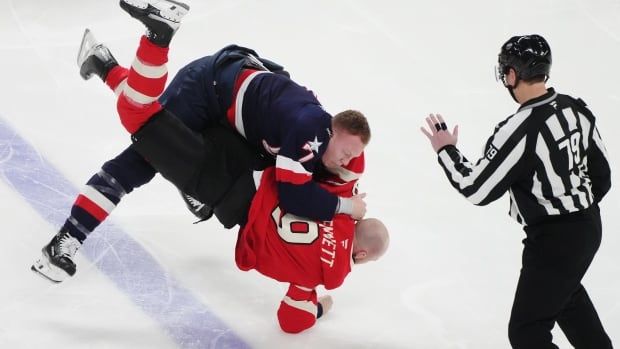 A male ice hockey player slams an opponent to the ice during a fight without helmets.