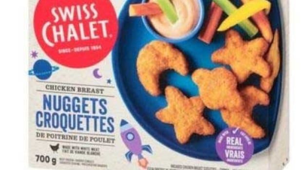 The front of a box of Swiss Chalet brand chicken nuggets, showing star, moon and planet-shaped chicken nuggets on a blue plate with dip and vegetable sticks.