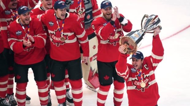 A group of men's players celebrate as one raises a trophy.