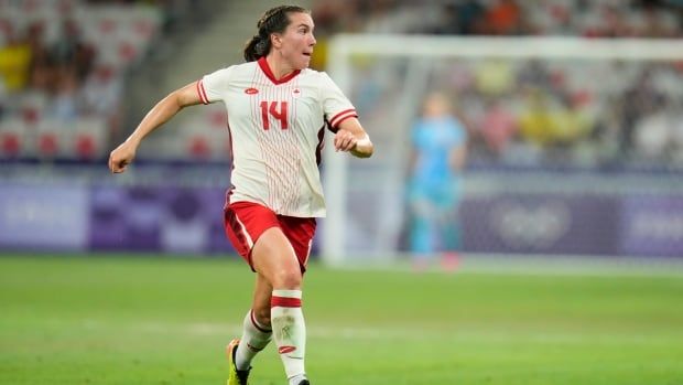 Female soccer player runs down soccer pitch.