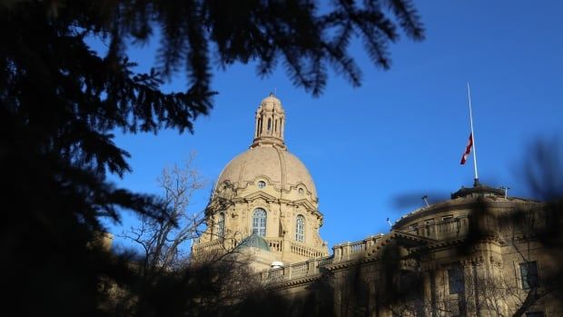 A view of the Alberta legislature, with a brown stone dome, under a blue sky.