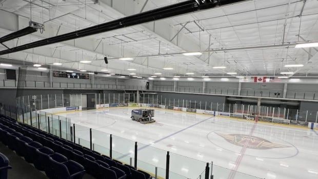 the inside of an arena showing the ice surface and some flags