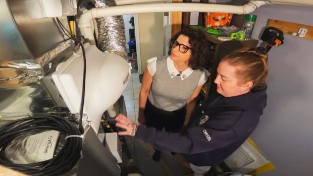 A high angle shot of a woman pointing to some filtration equipment, while another woman looks on.