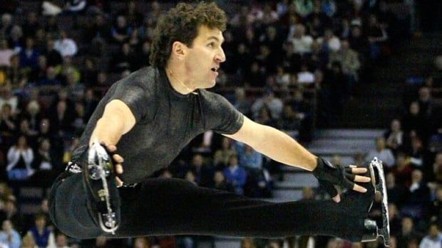 A man grabs his skates as he jumps in the air.