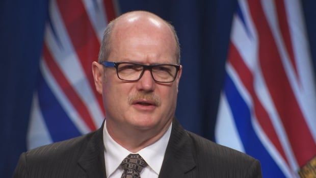 A man with glasses is pictured at a podium. 