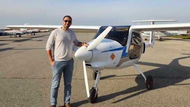 A man standing in front of a plane in an airfield.