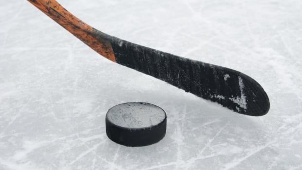 Ice hockey stick and a puck on ice