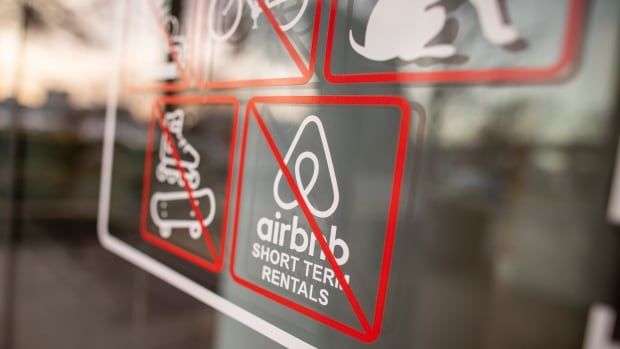 A sign on an apartment tower window indicates no Airbnb short-term rentals, no skateboarding, etc.