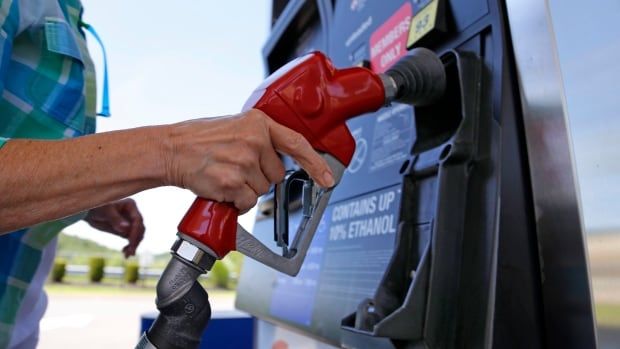 Woman lifting nozzle off gas pump.