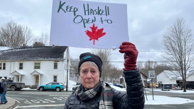 woman holding up sign saying Keep Haskell open to Canadians