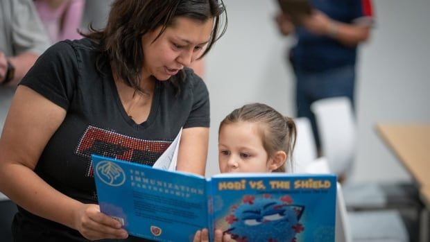 Priscilla Luna, left, and her 3 year-old daughter, read a book about immunizations at a vaccine clinic in Lubbock, Texas, on March 1. Cases of measles are on the rise in Texas and in southwestern Ontario. 