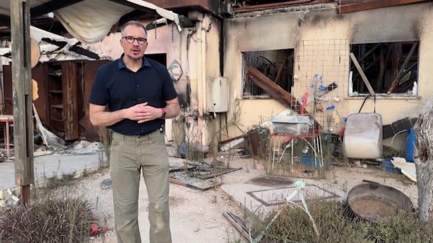 A man stands next to a destroyed building