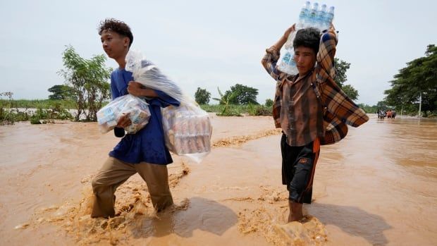 Local residents carrying food wade through a flooded road.