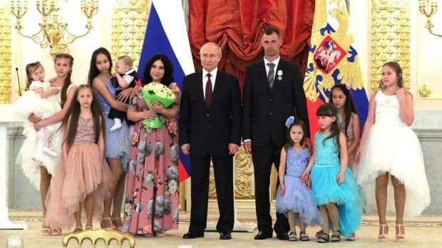 Lilia Syropyatova stands with her husband and their 9 children alongside Russian President Vladimir Putin, who awarded them with the Russian honour of "Parental Glory." "