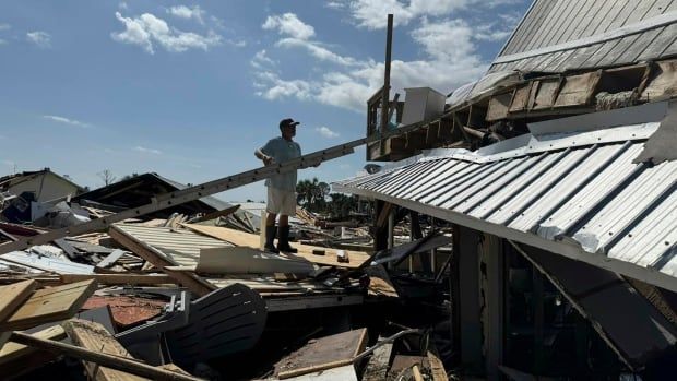 A man stands in the rubble of a home