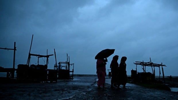 Villagers walk along a beach near Digha, India, ahead of the arrival of tropical storm Dana.