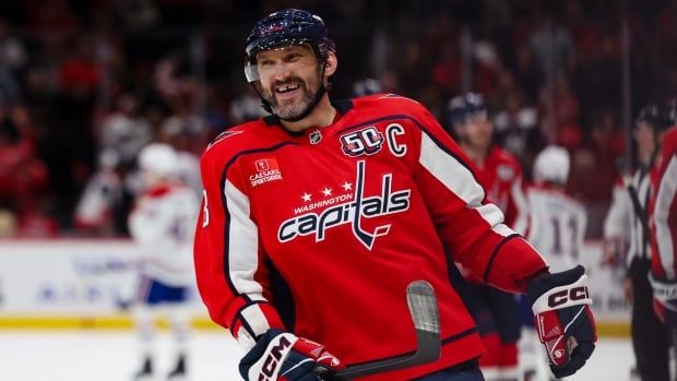 A men's hockey player smiles after scoring a goal.