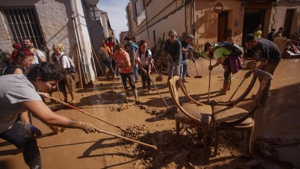 Residents and volunteers clean up an area affected by floods.