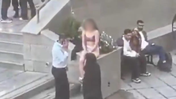 A woman is seen sitting on a concrete staircase in her underwear on a university campus.