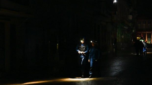 Rescue workers walk along a darkened street in Havana after Hurricane Rafael passed through.