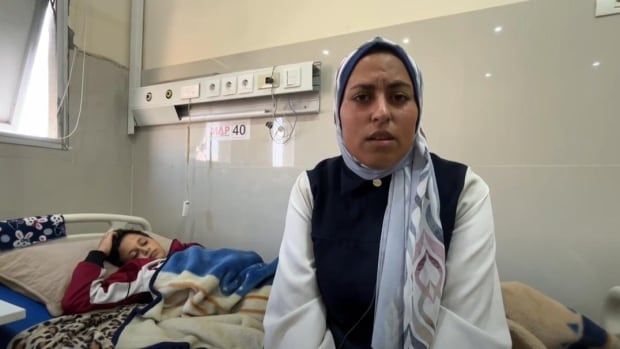 A woman lays on a hospital bed next to a young boy.