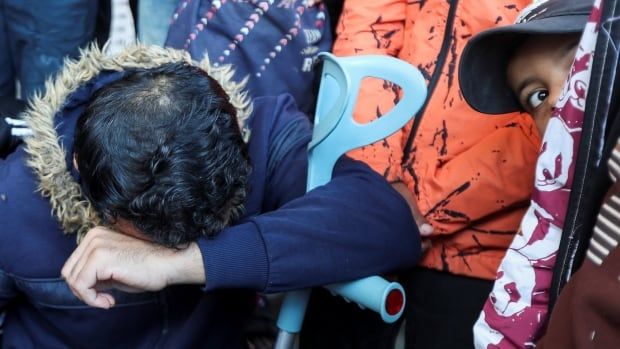 A boy looks on as a mourner reacts.