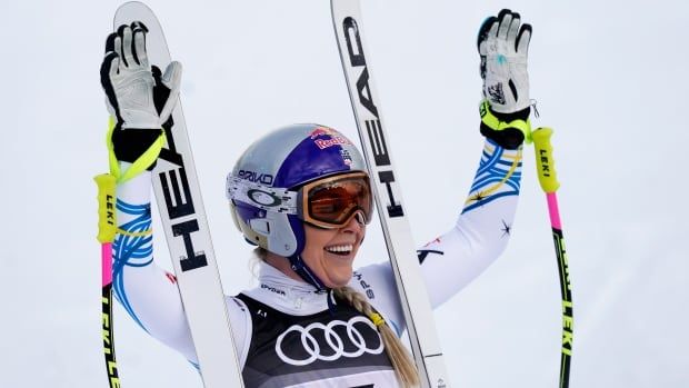 A women's alpine skier raises her arms in celebration.