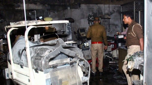 Police officers inspect fire-damaged equipment in a neonatal intensive care unit.