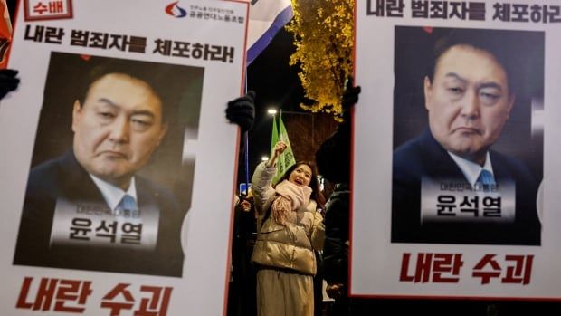 Protesters in Seoul hold up placards that condemn South Korean President Yoon Suk Yeol's push for martial law and call for his resignation from office.