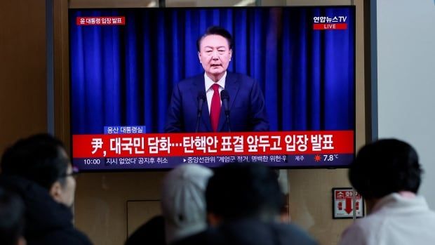 People watch the live broadcasting of South Korean President Yoon Suk Yeol delivering an address to the nation, at a railway station in Seoul, South Korea, December 7, 2024. 