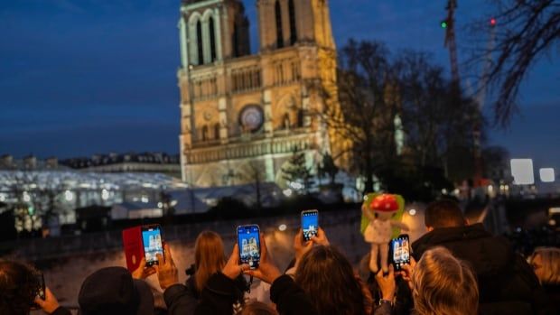 People take cellphone photos of Notre Dame cathedral.