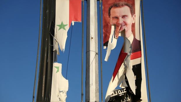 A blue sky in the background with torn flags on each side of a metal pole.