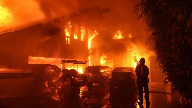 A firefighter sprays water on a home as it burns in the Franklin Fire in Malibu.