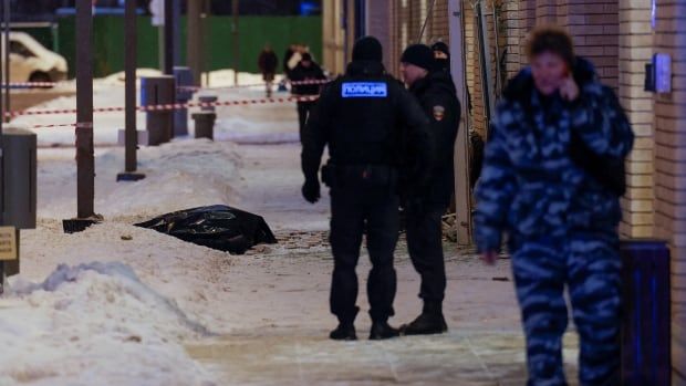 A body bag is shown on a snow-covered sidewalk.