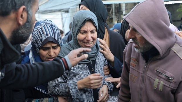 A pair of women cry while men stand at their side