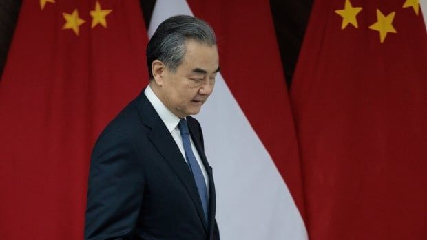 A man in a suit walks past the Chinese flag.