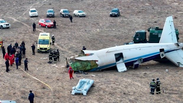 People and emergency vehicles surround a wrecked plane.