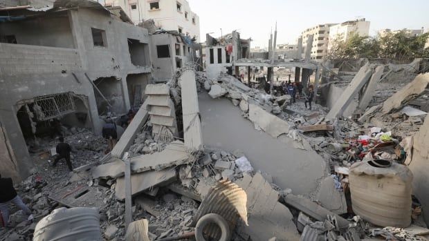 Palestinians inspect the site of an Israeli airstrike on a house.