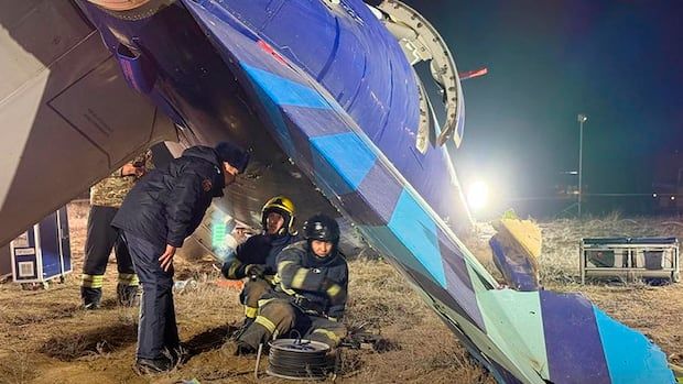 People crouch under a broken wing of a plane at night.