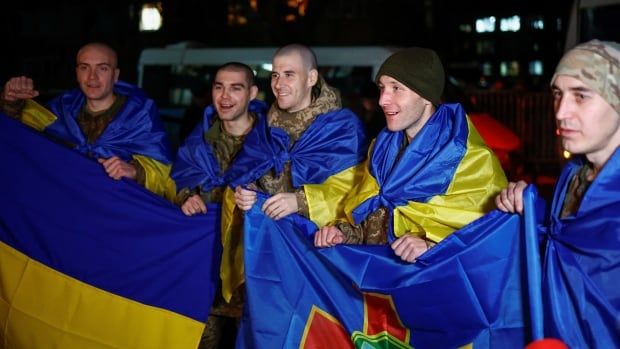 Ukrainian prisoners of war (POWs) wrapped with national flags react as they return after a swap, amid Russia's attack on Ukraine, in an undisclosed location in Ukraine.