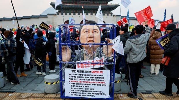 A figure of a man with his arms chained is pictured behind protesters.