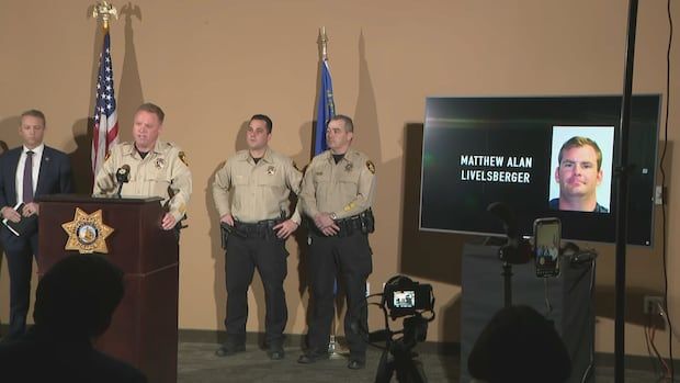 Police officers stand before a monitor with the picture of a suspect.