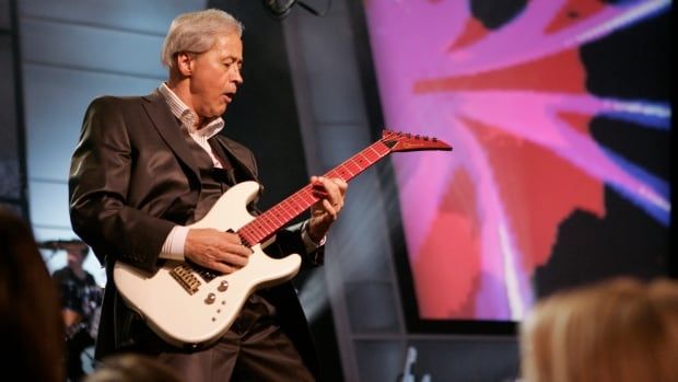 A man plays electric guitar on stage.