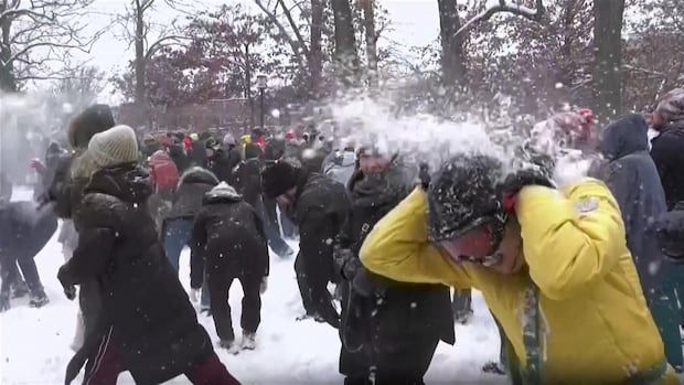 A snowball bursts after hitting someone in the middle of a large snowball fight.