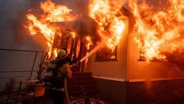 Firefighter hoses down a house on fire. 