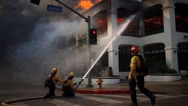 Firefighters use a hose to battle the flames of a burning building on Sunset Boulevard in the Pacific Palisades neighbourhood of Los Angeles.