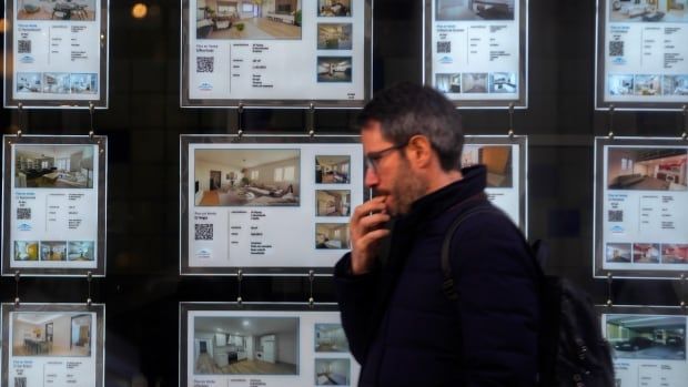 A man  walks past real estate listings