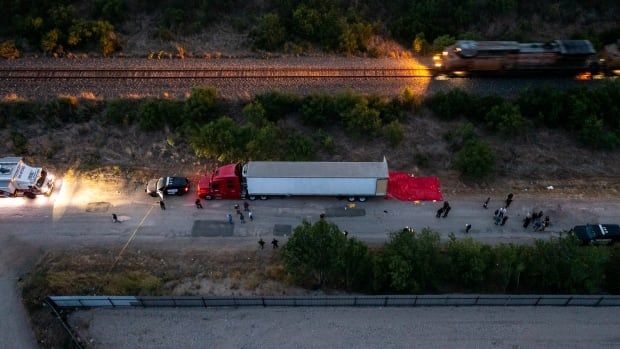 Bird's-eye view looking down at a truck parked on a road, with a train passing on tracks nearby.